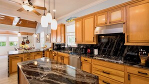 Una cocina moderna con armarios de madera, encimera de mármol y estufa empotrada.
