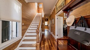 Una escalera de madera lleva a una zona de cocina con vista al exterior.