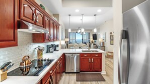 A modern kitchen with wooden cabinets, stainless steel appliances, and a view to the outside.