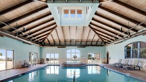 A large indoor swimming pool with a high ceiling and natural light from large windows.