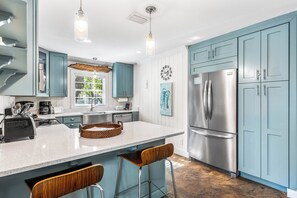Een moderne keuken met een centraal eiland, roestvrijstalen apparatuur en lichtblauwe keukenkastjes.