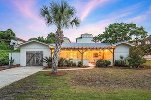 A house with a covered porch, a garage, and a well-maintained lawn.