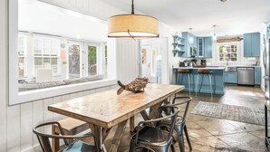 A modern kitchen with a wooden dining table, blue cabinets, and a hanging light fixture. - Seabreeze*FrangistaBeach*PrivatePool*Fenced for Dogs (Miramar Beach)