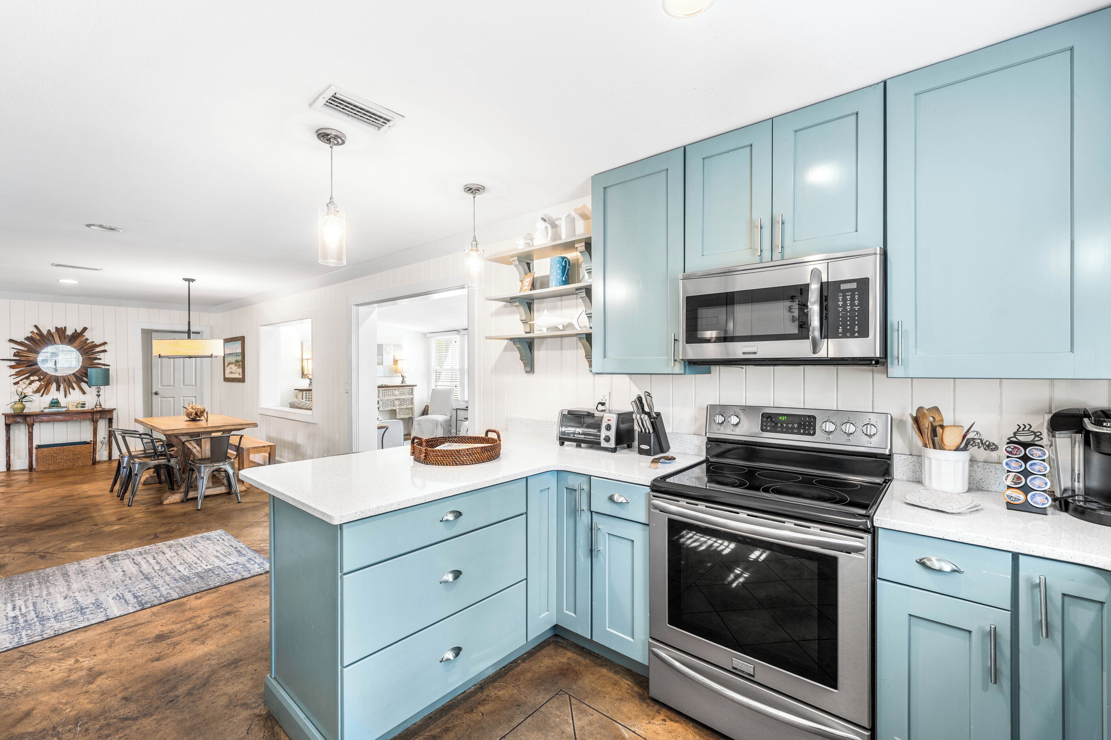 A modern kitchen with light blue cabinets, stainless steel appliances, and a white countertop.