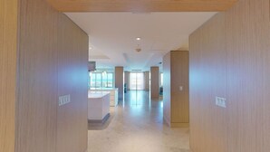 A modern hotel corridor with wooden paneling, a reception desk, and large windows offering a view of the interior. - Astonishing Oceanfront Residence Located at The Ritz-Carlton, Grand Cayman (Seven Mile Beach)