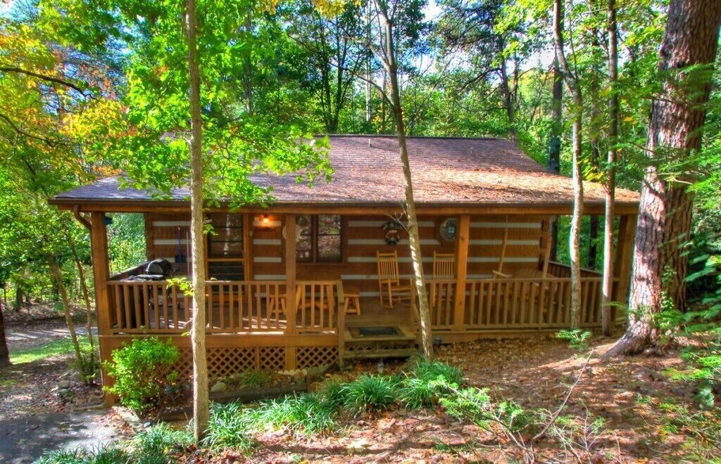 Eine rustikale Holzhütte mit einer Holzterrasse, umgeben von Bäumen.