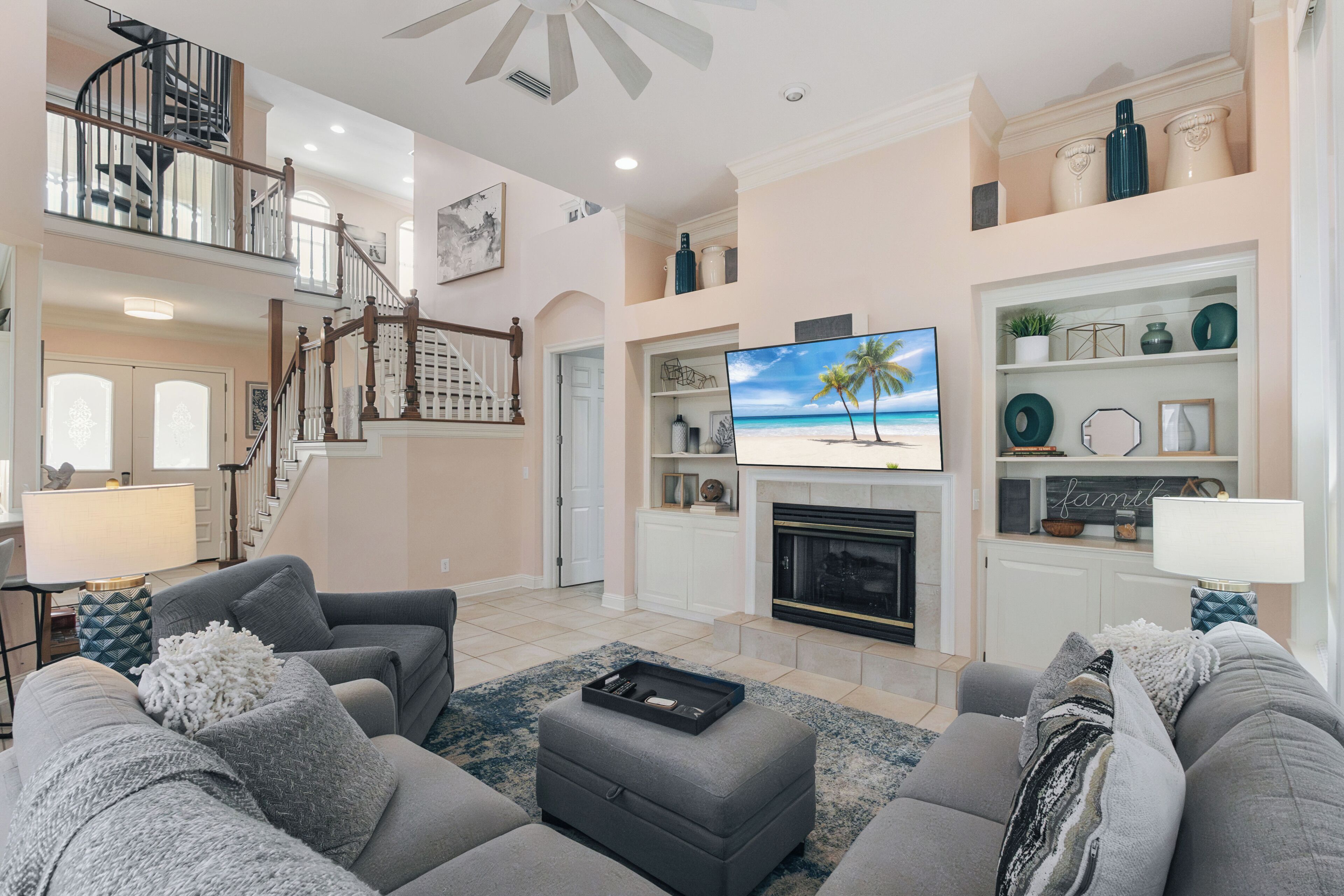 A spacious living room with a fireplace, a television, and a staircase leading to an upper level.