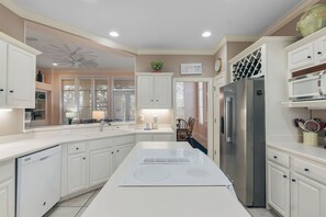 A modern kitchen with white cabinetry, a stainless steel refrigerator, and a built-in stove.