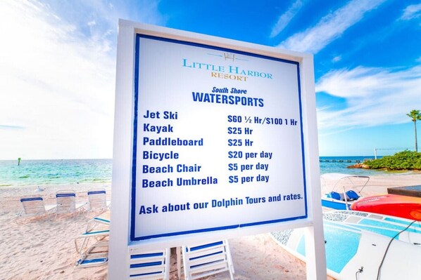 A sign listing watersports activities and prices at Little Harbor Resort.