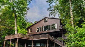 A two-story cabin with a deck and stairs, surrounded by trees. - Laurel View Retreat - Spacious Private Estate Experience (Hopwood)