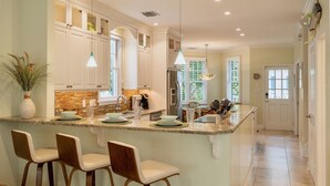 A modern kitchen with white cabinets, a central island with bar stools, and pendant lighting. - **BRISA FRESCA @ THE ANNEX** Airy Home + Last Key White Glove Service... (Key West)
