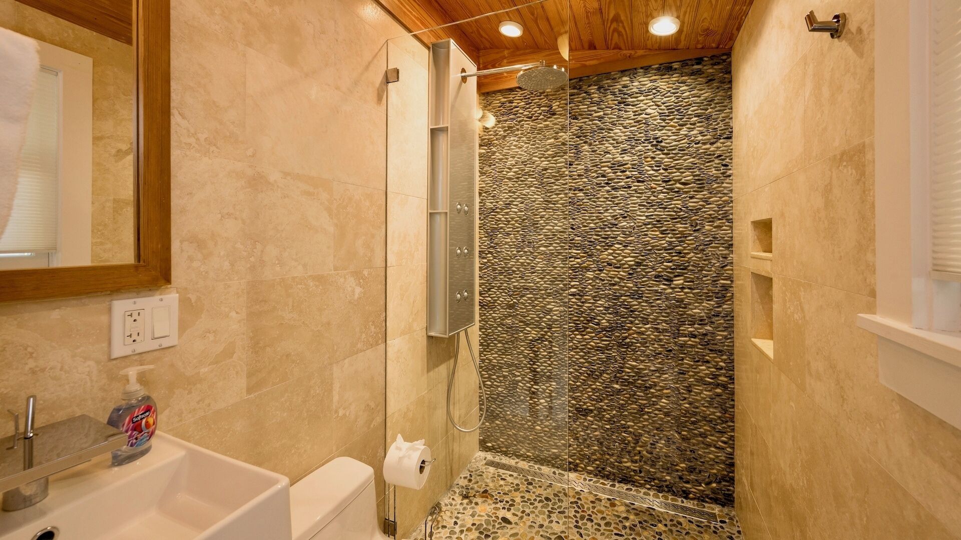 A bathroom with a stone wall, a shower, and a sink.