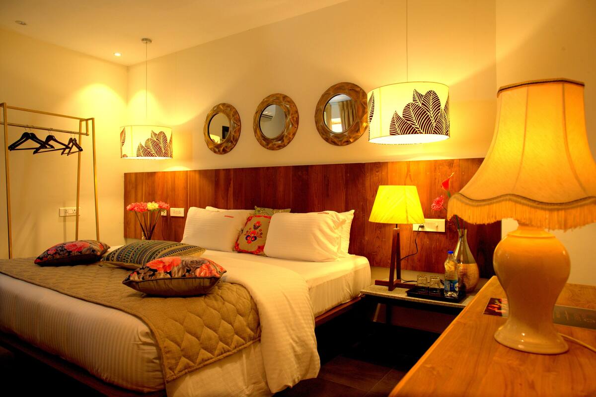 Ein Hotelzimmer mit Bett, Nachttisch, Lampe und Spiegeln an der Wand.