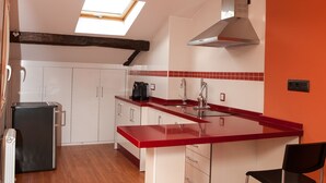 A kitchen with a red countertop, white cabinets, a black refrigerator, and a skylight. - Authentic attic in the center of Béjar (Béjar)