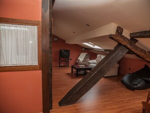 A loft-style living room with a sloped ceiling, wooden beams, and a large window with sheer curtains. - Authentic attic in the center of Béjar (Béjar)