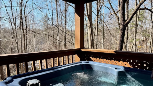 A hot tub on a wooden deck with a view of leafless trees in the background.