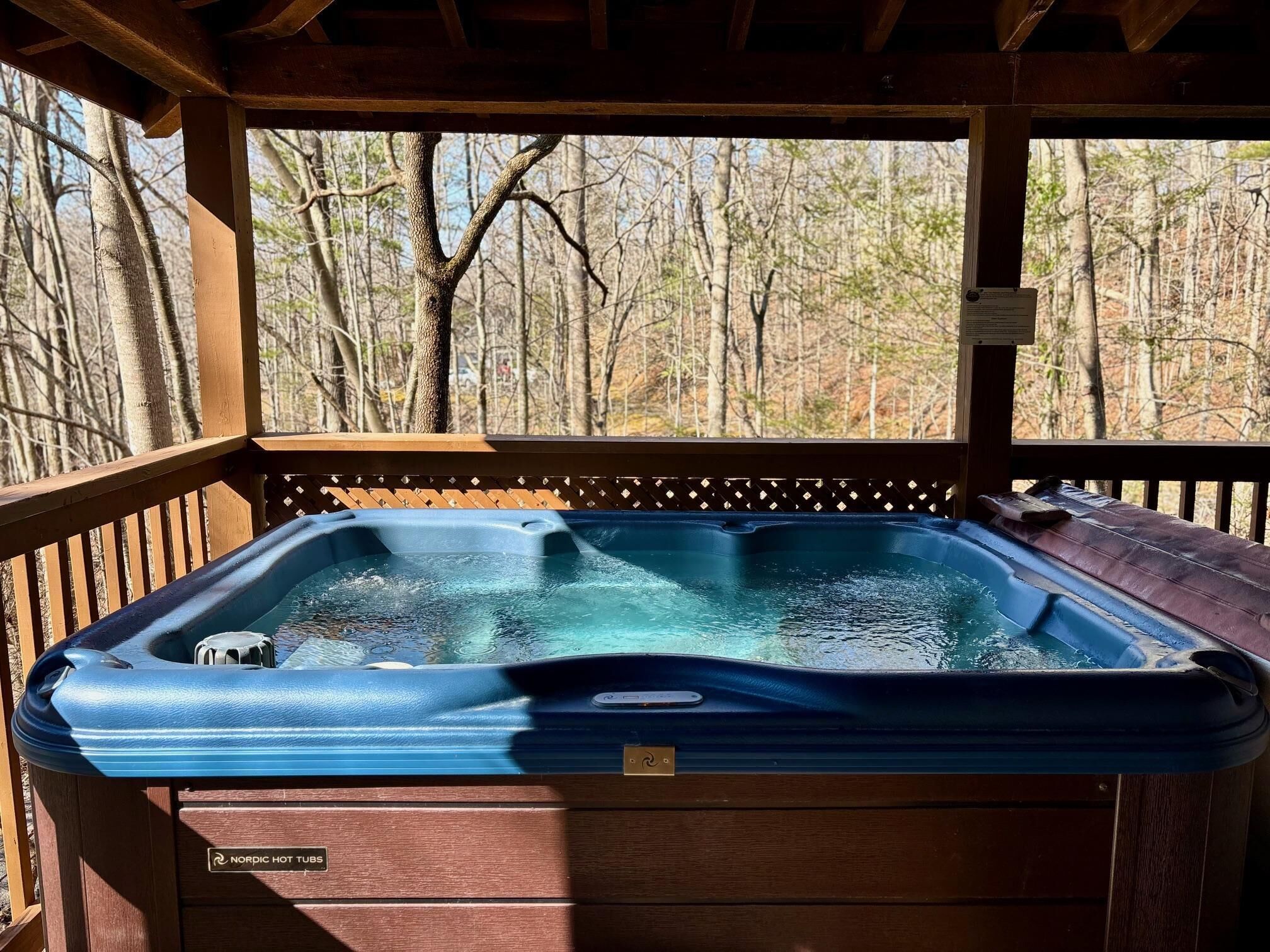 Un jacuzzi en una terraza de madera con vistas a un bosque.