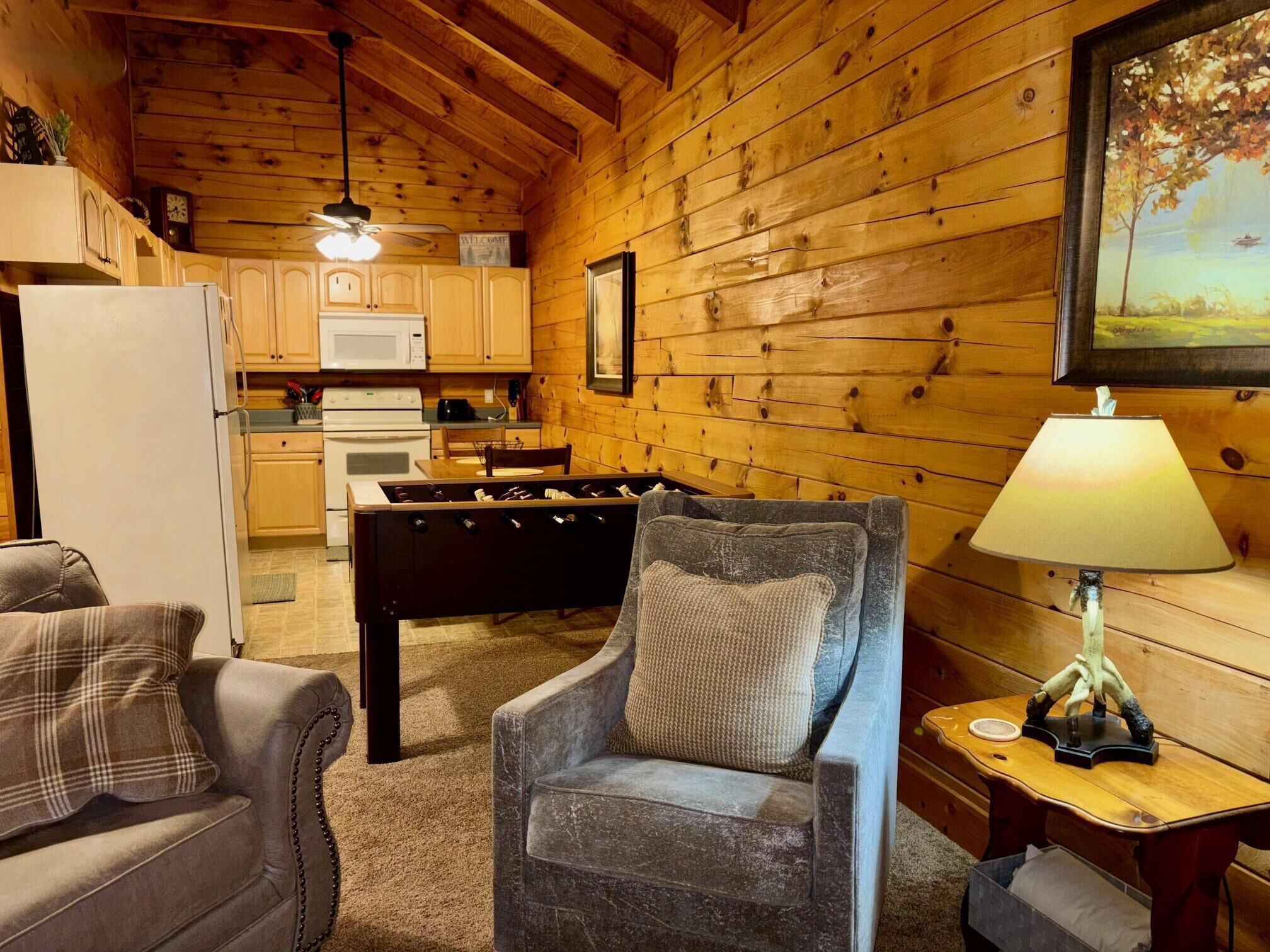 A cozy log cabin interior with a dining area, kitchen, and seating space.