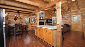 Interno di una baita di legno con cucina, zona pranzo e soggiorno.