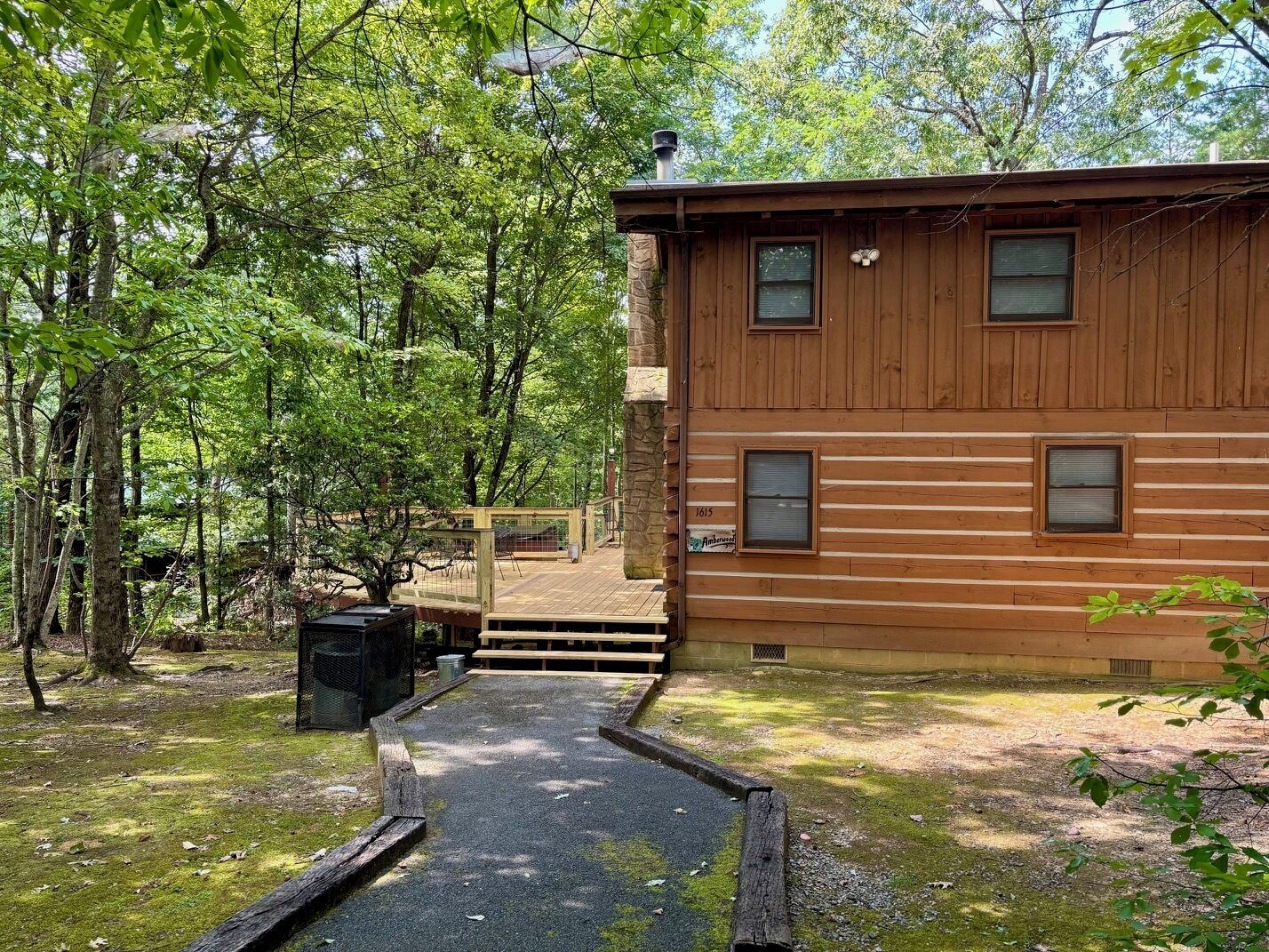 Une cabane en bois dotée d’une terrasse, entourée d’arbres.