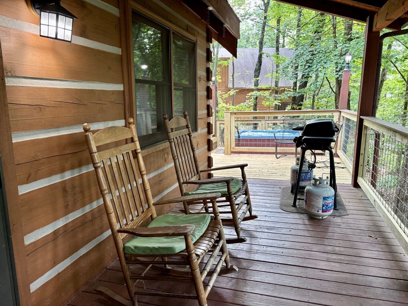 Eine Holzveranda mit zwei Schaukelstühlen und einem Grill.