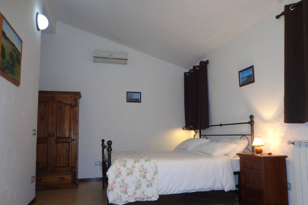 Une chambre à coucher avec un lit, une table de chevet, une lampe et une armoire en bois.