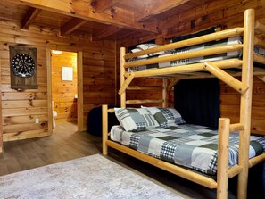 A bunk bed with a checkered blanket, a dartboard, and a wooden wall. - Pet friendly, hot tub, cozy log cabin sleeps 7! (Sevierville)