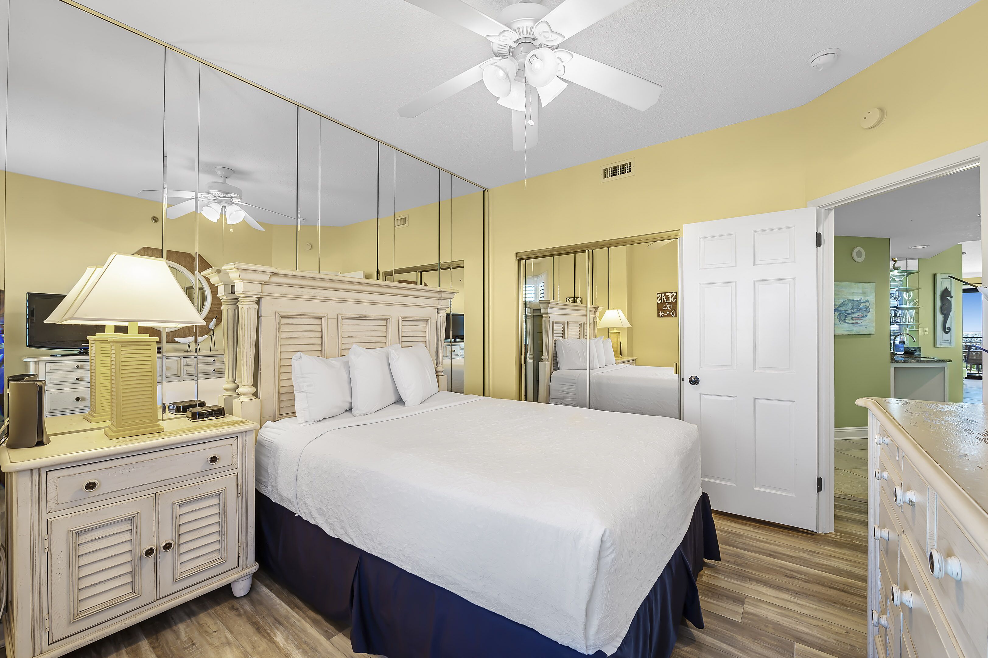 A hotel room with a bed, bedside table, lamp, and a ceiling fan.
