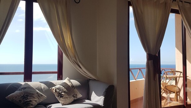 Ein Wohnzimmer mit einer Couch, einem Couchtisch und Meerblick durch große Fenster.
