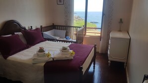 Ein Schlafzimmer mit Bett, Babybett und Meerblick.
