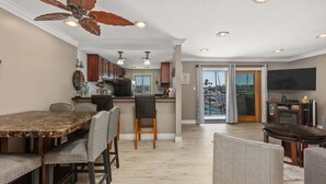 A spacious kitchen with a dining area, a ceiling fan, recessed lighting, and a view through the glass door. - Beachfront Condo with Heated Pool and Hot Tub | 311B (Oceanside)