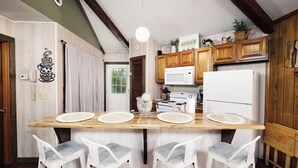 A kitchen with wooden cabinets, a microwave, a refrigerator, and a dining table with four chairs.