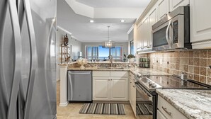 A modern kitchen with stainless steel appliances, white cabinetry, and a large island with a sink. - 604W - Beachfront condo with Amazing views! (Orange Beach)