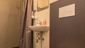 A bathroom with a toilet, sink, shower, and a mirror.