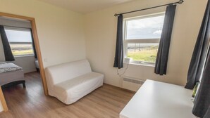 A room with a white bed, a white table, and a window with curtains.
