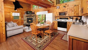 A cozy cabin interior with a dining area, kitchen, and a fireplace. - Great location with hot tub and pool table! Cute and classy log cabin! (Sevierville)