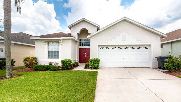 A single-story house with a red door, a garage, and a well-maintained lawn. - Modern Villa w/ South-Facing Pool, Spa & Game Room Near Disney (Kissimmee)