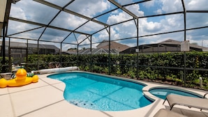 A swimming pool with a glass enclosure, surrounded by greenery and lounge chairs. - Modern Villa w/ South-Facing Pool, Spa & Game Room Near Disney (Kissimmee)