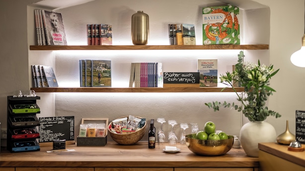 A bookstore shelf with books, a vase with green plants, and a chalkboard menu. - Hotel Goldene Steig (Kempten)