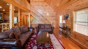 A wooden interior with a sofa, coffee table, and a staircase leading to an upper level.