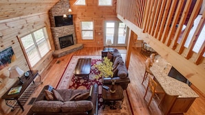 A spacious living area with a fireplace, wooden ceiling, and a dining area with a kitchen counter.