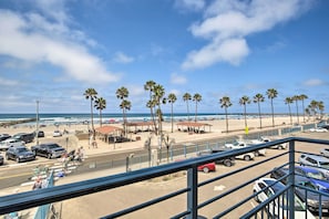 Une vue sur la plage avec un espace de stationnement, des parasols et des palmiers.