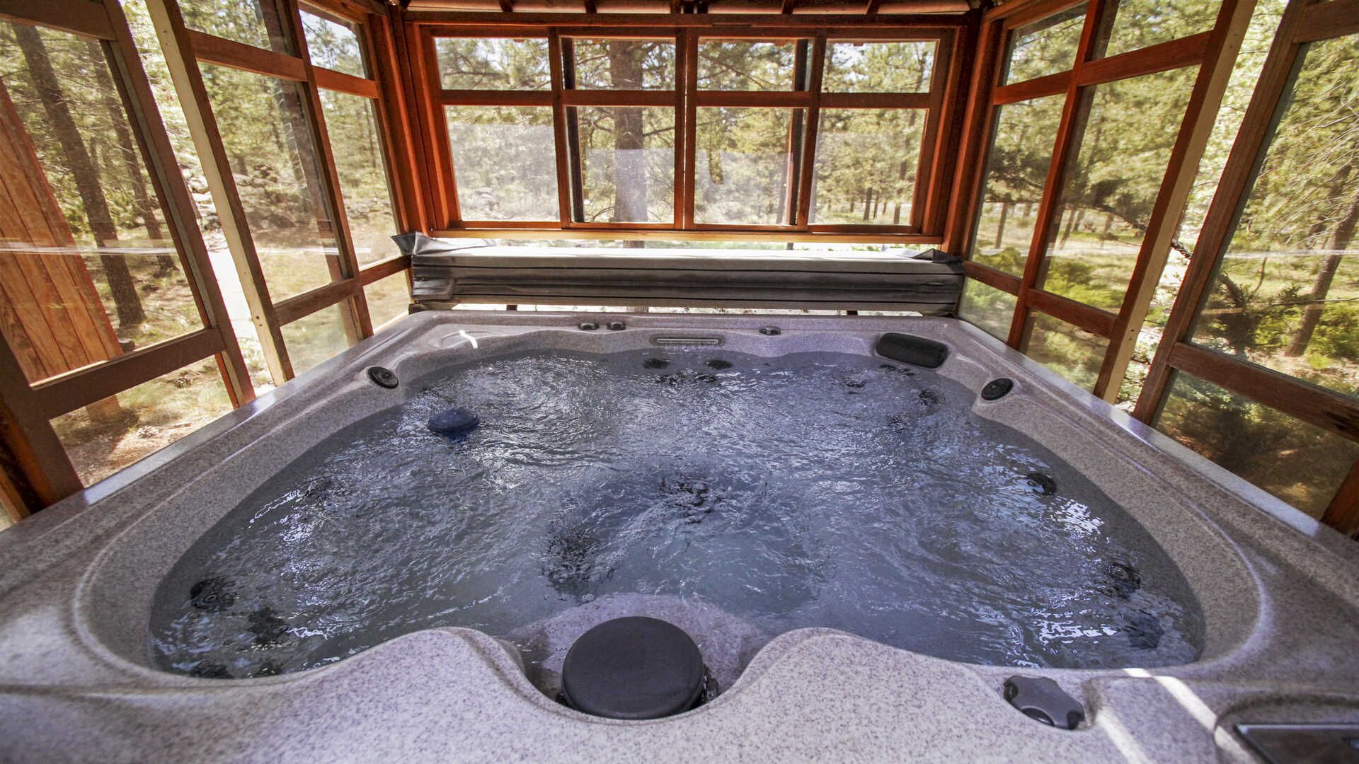 A hot tub with a stone interior, surrounded by wooden walls and large windows.