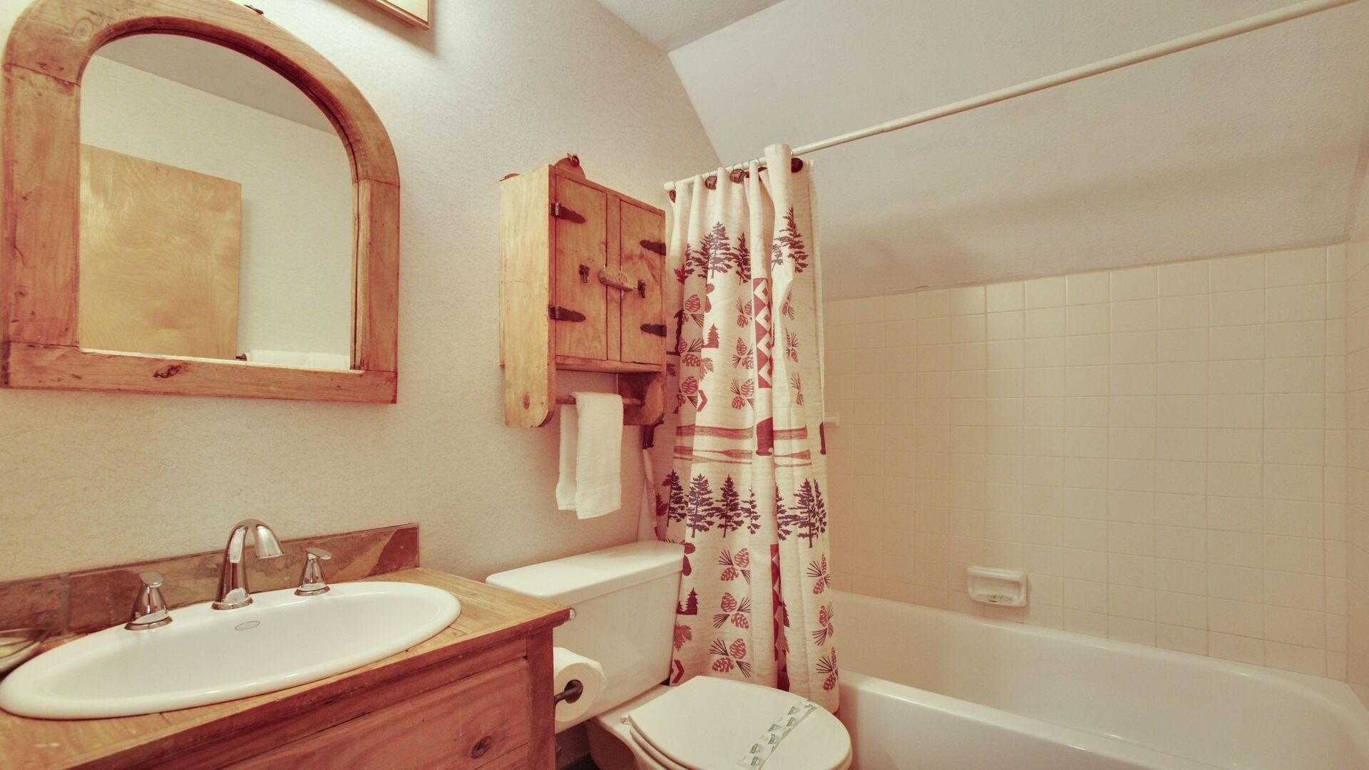 A bathroom with a wooden vanity, a sink, a toilet, and a bathtub.