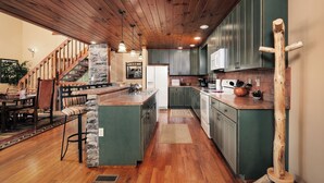 A spacious kitchen with wooden cabinets, a stone accent wall, and a central island. - Mountain views, pet friendly, game rooms, 3 king bedrooms, and 2 game rooms! (Sevierville)