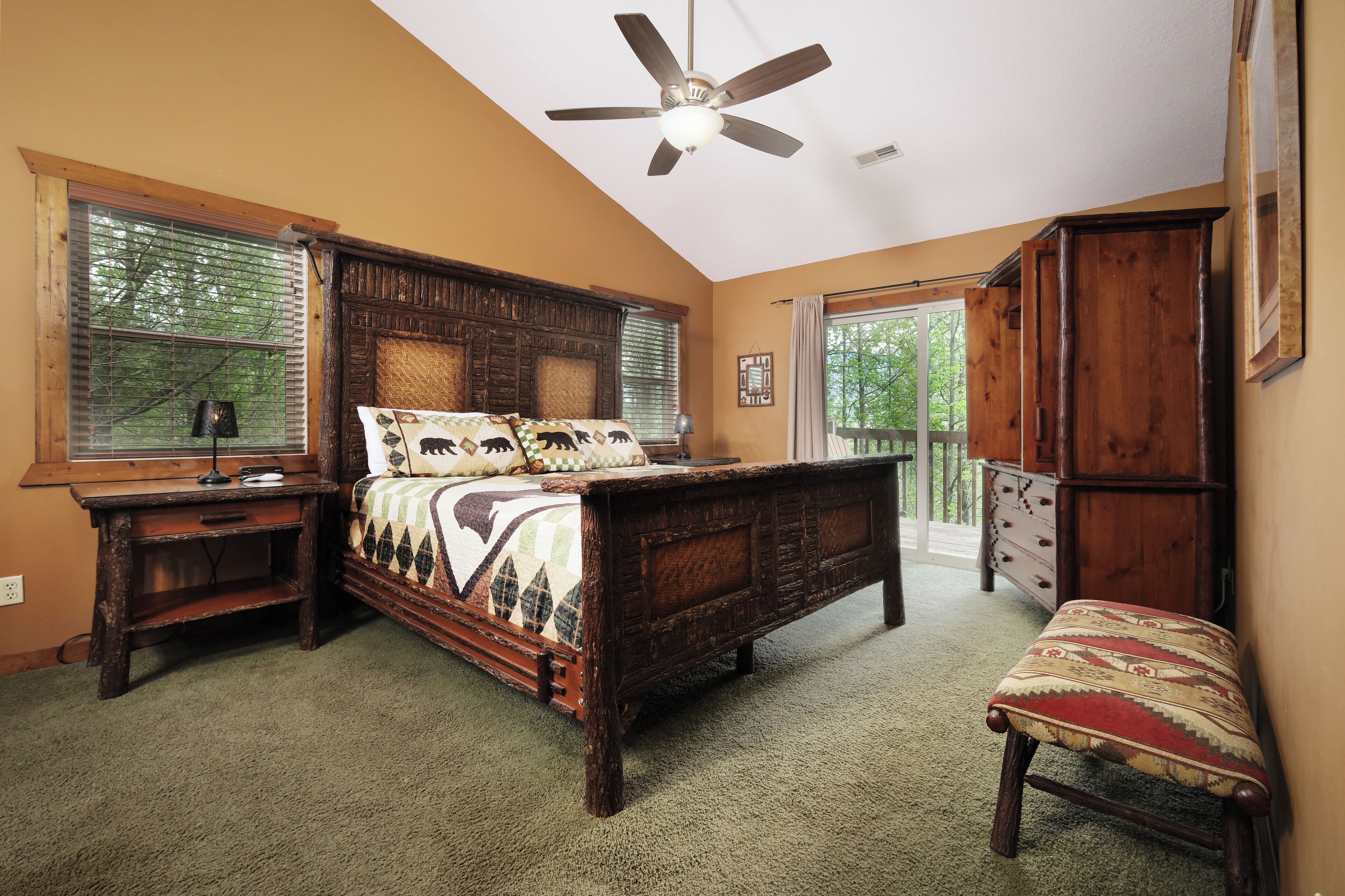 A bedroom with a wooden bed, a nightstand, a bench, and a ceiling fan.