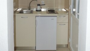 Una cucina compatta con frigorifero, lavello e finestra sopra il piano di lavoro.