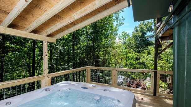 Un jacuzzi en una terraza de madera con vista a un bosque.