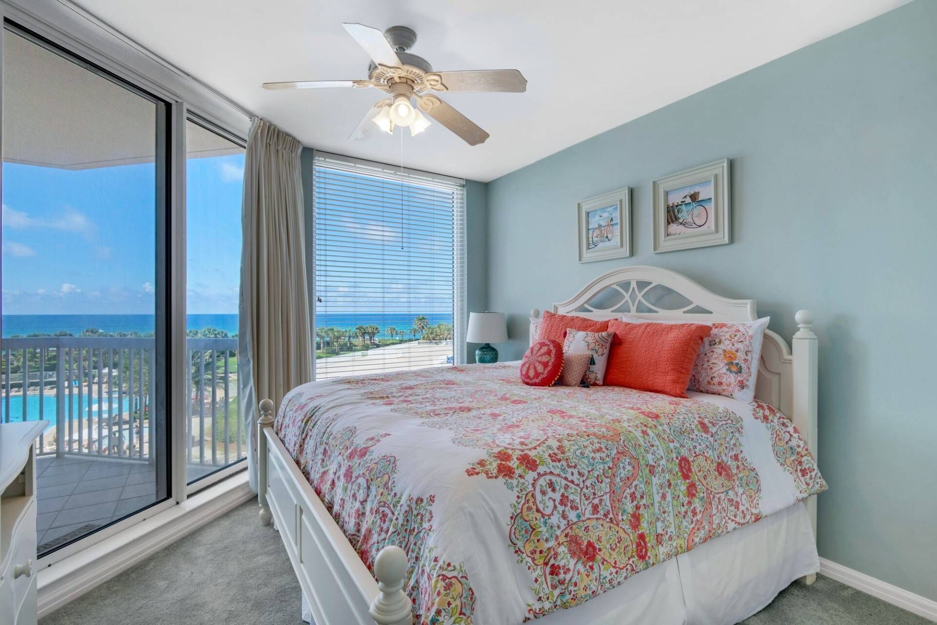 Ein Schlafzimmer mit Bett, Deckenventilator, Meerblick und einem Balkon.