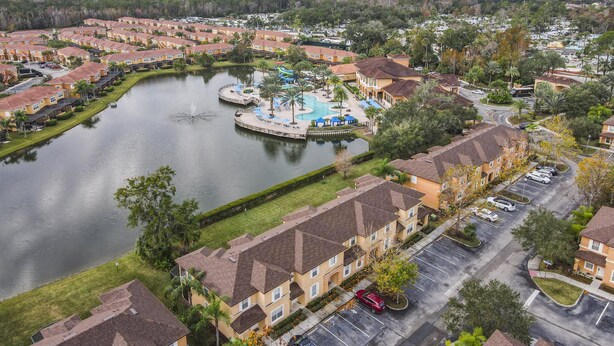 Zona residencial con un lago central, piscina y aparcamiento.